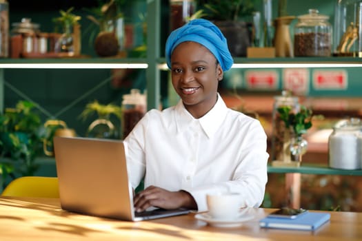 Happy african woman independent contractor working from cafe, copy space