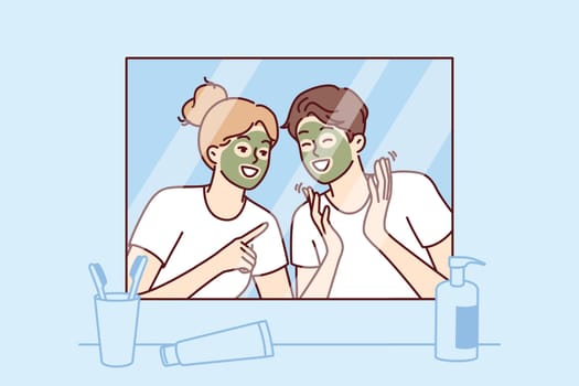 Cheerful couple with rejuvenating mask on faces look in mirror and laugh enjoying joint vacation