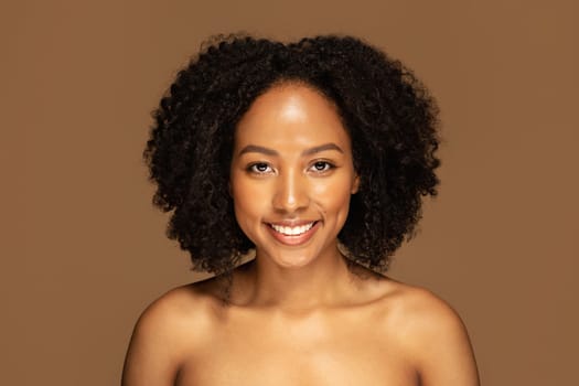 Attractive black woman with bushy hair posing naked on brown