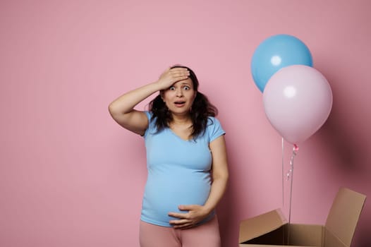 Emotional surprised woman feeling shock at gender party, expecting twins boy and girl, holding head and touching belly