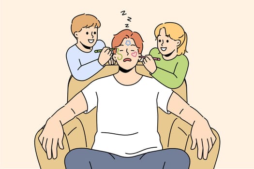 Naughty smiling children draw on sleeping father face