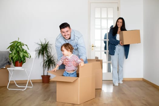 Happy Family Riding Their Son In Cardboard Box While On Moving Day
