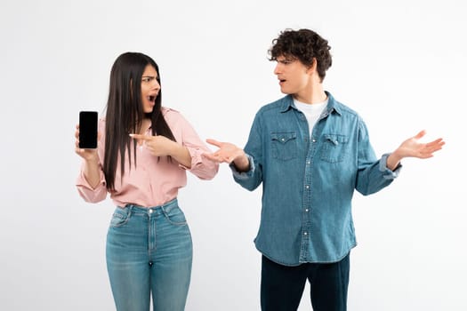 Angry Girlfriend Showing Phone Screen To Confused Boyfriend, White Background