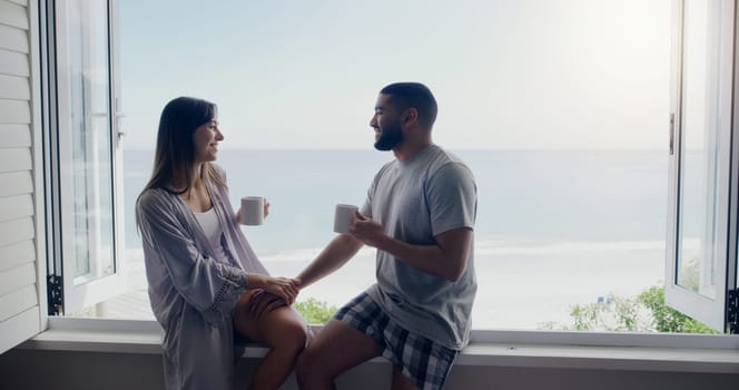 Couple, coffee and window on holiday by sea with conversation, romance and love in summer sunshine. Woman, man and drink with latte, morning or matcha on vacation with ocean view in home with bond.