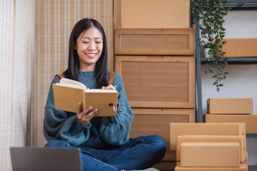 Young beautiful happy asian business woman owner of SME online using laptop receive order from customer with parcel box packaging at her startup home office, online business seller
