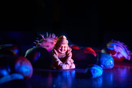 Statuette of a Buddhist monk among various stones in blue night light