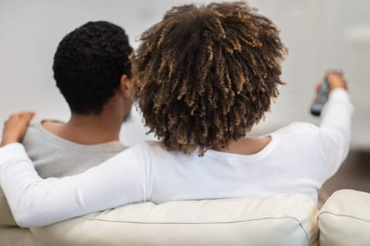 Rear view of black couple watching TV at home