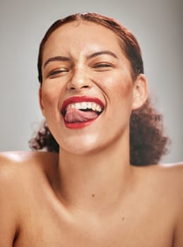 Beauty, face and woman, lipstick and makeup with tongue out and teeth, skin and happy isolated on studio background. Crazy, flirt and red lips with skincare and glow from cosmetic care and portrait