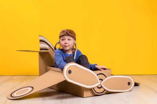 Little dreamer girl playing with a cardboard airplane. Childhood. Fantasy, imagination.