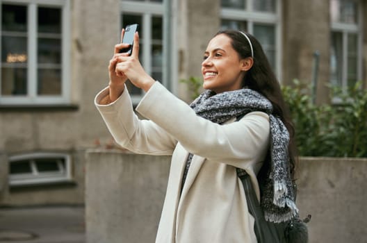 Travel, tourism and phone with a woman in the city taking a photograph while traveling on holiday or vacation. Tourist, traveler and mobile with a female photographing while sightseeing abroad