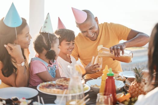 Birthday, parents and children with juice by beach for event, celebration and outdoor party together. Family, social gathering and mother, dad and kids at picnic with cake, presents and eating food