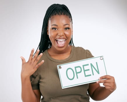 Black woman, excited and holding open sign for announcement or message against a grey studio background. Portrait of African American female manager advertising startup opening or ready for service