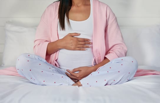 Pregnant, hands on stomach and woman in bed holding belly for baby, infant and affection at home. Pregnancy love, family and excited, loving and happy mother rest, relaxing and calm in bedroom.