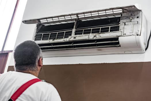 Repairman checking and repairing air conditioner indoors