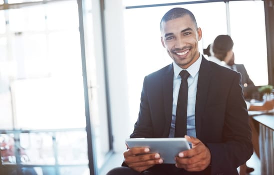 Convenience and connectivity are indispensable to the modern executive. Portrait of a young businessman using a digital tablet during a meeting at work.