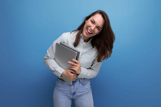 IT specialist 25 year old brunette woman in shirt and jeans enjoys freelancing holding a laptop in her hand