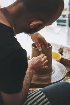 Curiosity is the key to creativity. an unrecognisable man working with clay in a pottery studio.