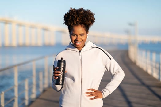 African American Female Jogger With Water Bottle In Hands Posing Outdoors