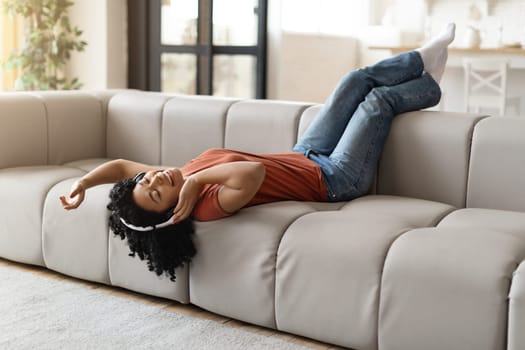 Favorite Pastime. Black Woman Lying On Couch And Listening Music In Headphones