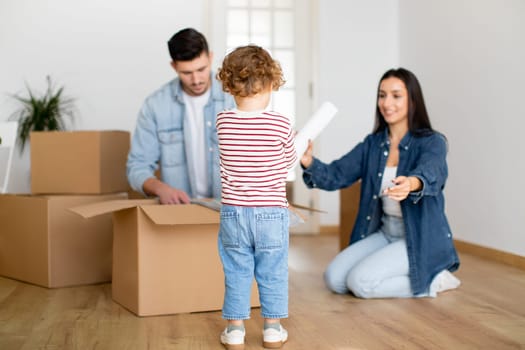 Family Unpacking Cardboard Box With Belongings After Moving To New Home