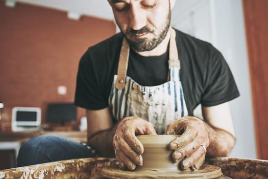 Creativity keeps the soul calm. a young man working with clay in a pottery studio.