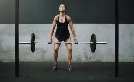 Strong, weight lifting and woman with barbell in gym for training, exercise and intense workout. Fitness, deadlift and female body builder lift weights for challenge, wellness and muscle strength
