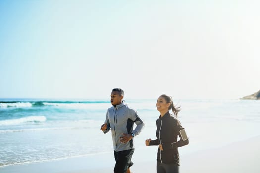 Your wellbeing matters. a sporty young couple out for a run along the beach.