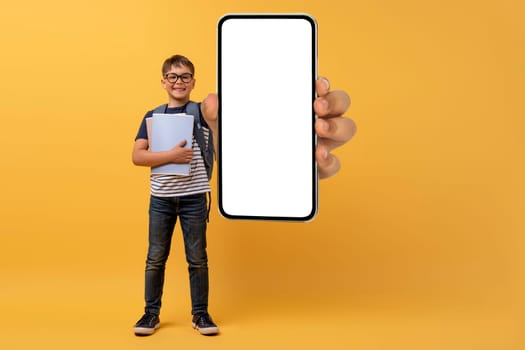 Educational App. Excited Schoolboy Pointing At Smartphone With Blank Screen