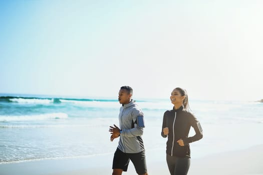 Fresh air and exercise. a sporty young couple out for a run along the beach.
