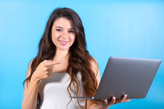 Brunette young woman with amused expression looks at laptop