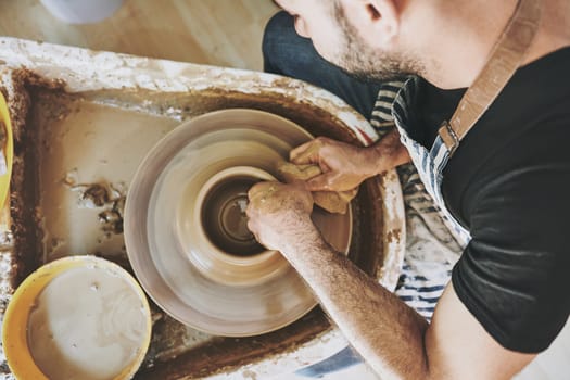 Imagine it, then make it. an unrecognisable man working with clay in a pottery studio.