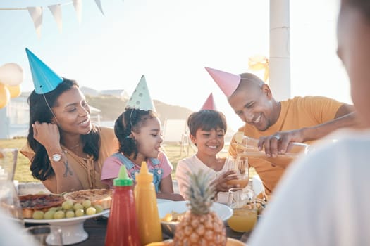 Birthday, parents and kids with food in park for event, celebration and party outdoors together. Family, social gathering and mother, father with children at picnic with juice, presents and cake