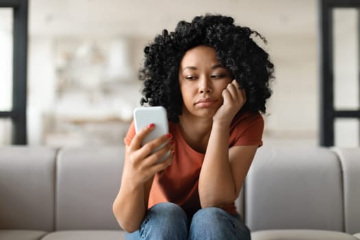Bored Young Black Female Looking At Smartphone Screen At Home
