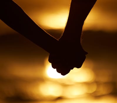 Couple, silhouette and holding hands at sunset on a beach for vacation or holiday outdoor. Closeup of man and woman in nature for peace, calm and love at ocean for creative shadow, travel or freedom