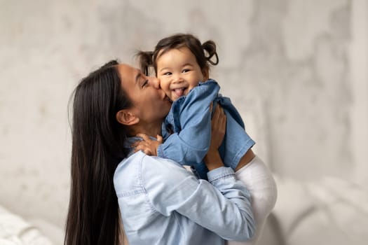 Asian Baby Sticking Out Tongue As Mommy Kissing Her Indoor