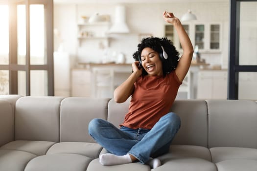 Cheerful Black Woman Listening Her Favorite Music In Wireless Headphones At Home