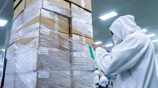 Safety and quality inspector inventorying product packed in cardboard boxes at a food processing plant