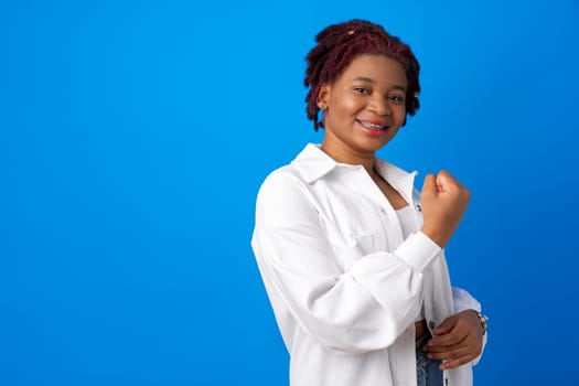 African American woman feeling strong, showing fist against blue background