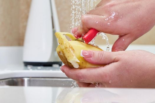 woman peeling potatoes over a sink, closeup view