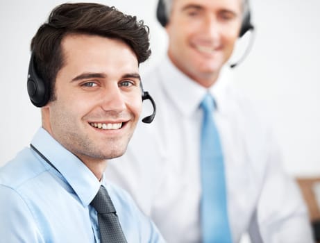 Pleased to be of service. Male customer service agents at work while wearing headsets.
