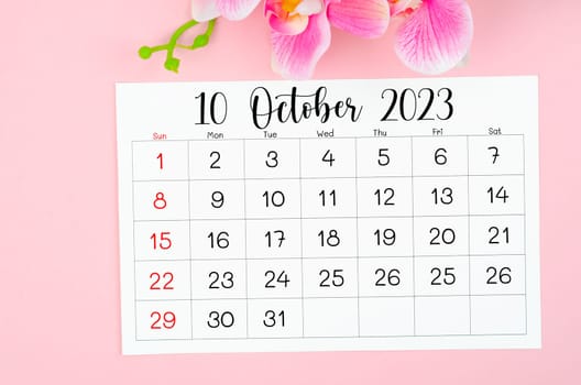 The October 2023 calendar page and pink orchid on pink background.