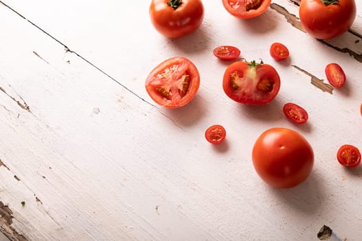 Overhead view of fresh red tomato variations on white wooden table