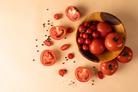 Directly above view of fresh tomato variations in bowl by peppercorn and halves on table