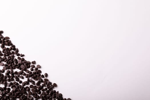 Overhead view of copy space by fresh chocolate chips over white background