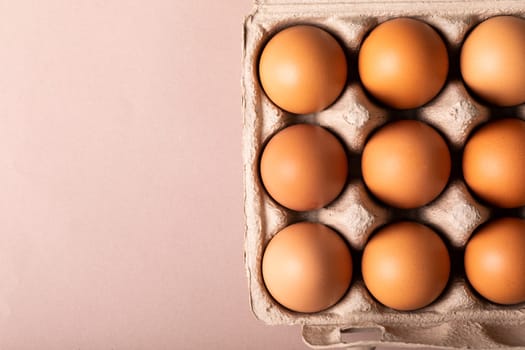 Directly above view of fresh brown eggs in carton by copy space on colored background. unaltered, food, healthy eating concept.