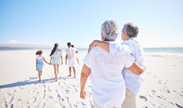 Big family, sea or old couple walking with children in summer with happiness, trust or peace in nature. Grandparents, back view or senior man bonding with woman or kids taking a walk on beach sand