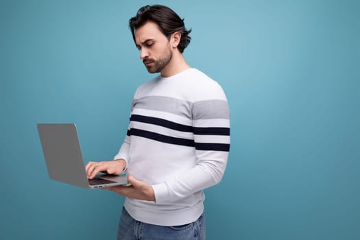 handsome well-groomed young brunette male freelancing using laptop