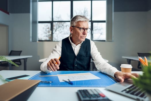 Mature man working on architectural project in office