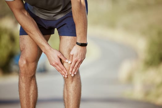 Man, hands and runner with knee pain in fitness, injury or sore inflammation on bone in the outdoors. Hand of male person or athlete holding painful leg area in sport accident or bruise from running