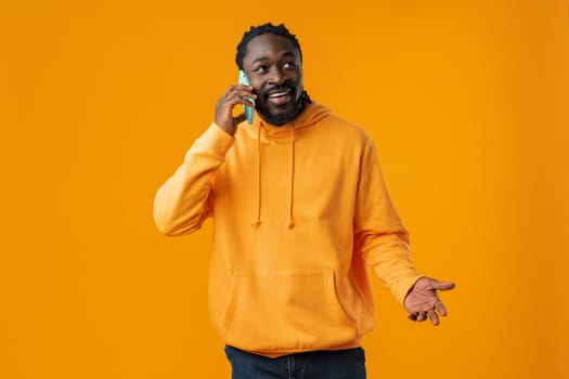 Young black man making a phone call against yellow background
